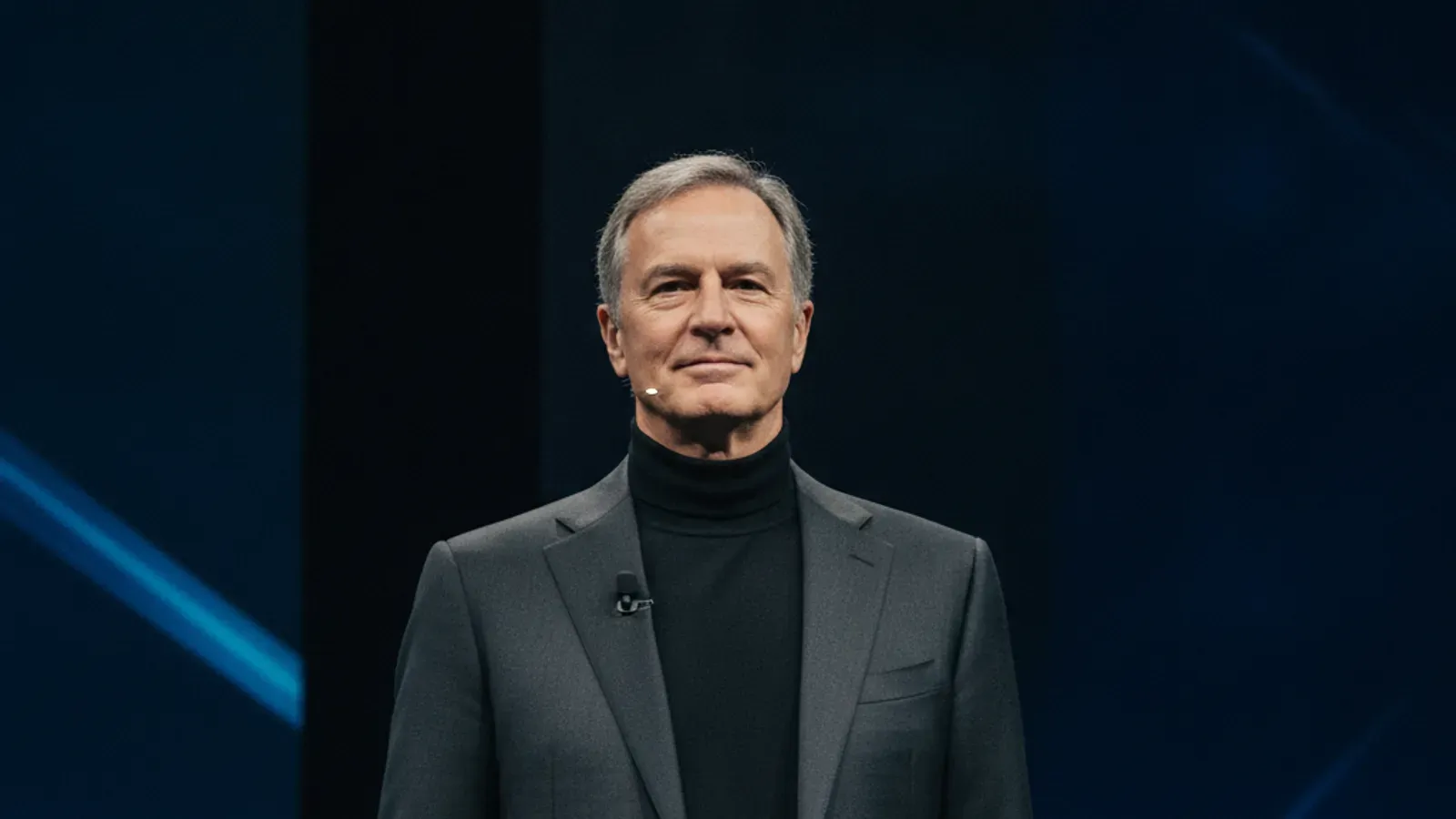 Larry Ellison'ın sahnede koyu renk takım elbisesi ve balıkçı yaka kazağıyla portresi.