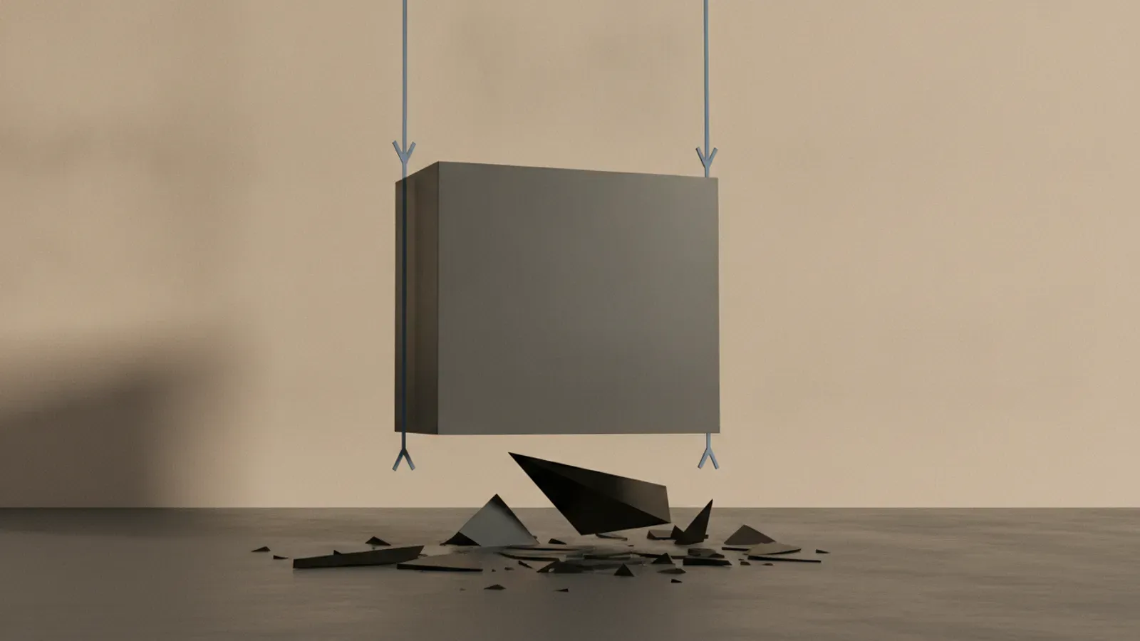 A large grey cube suspended by thin cables directly over a floor scattered with shattered black shards.